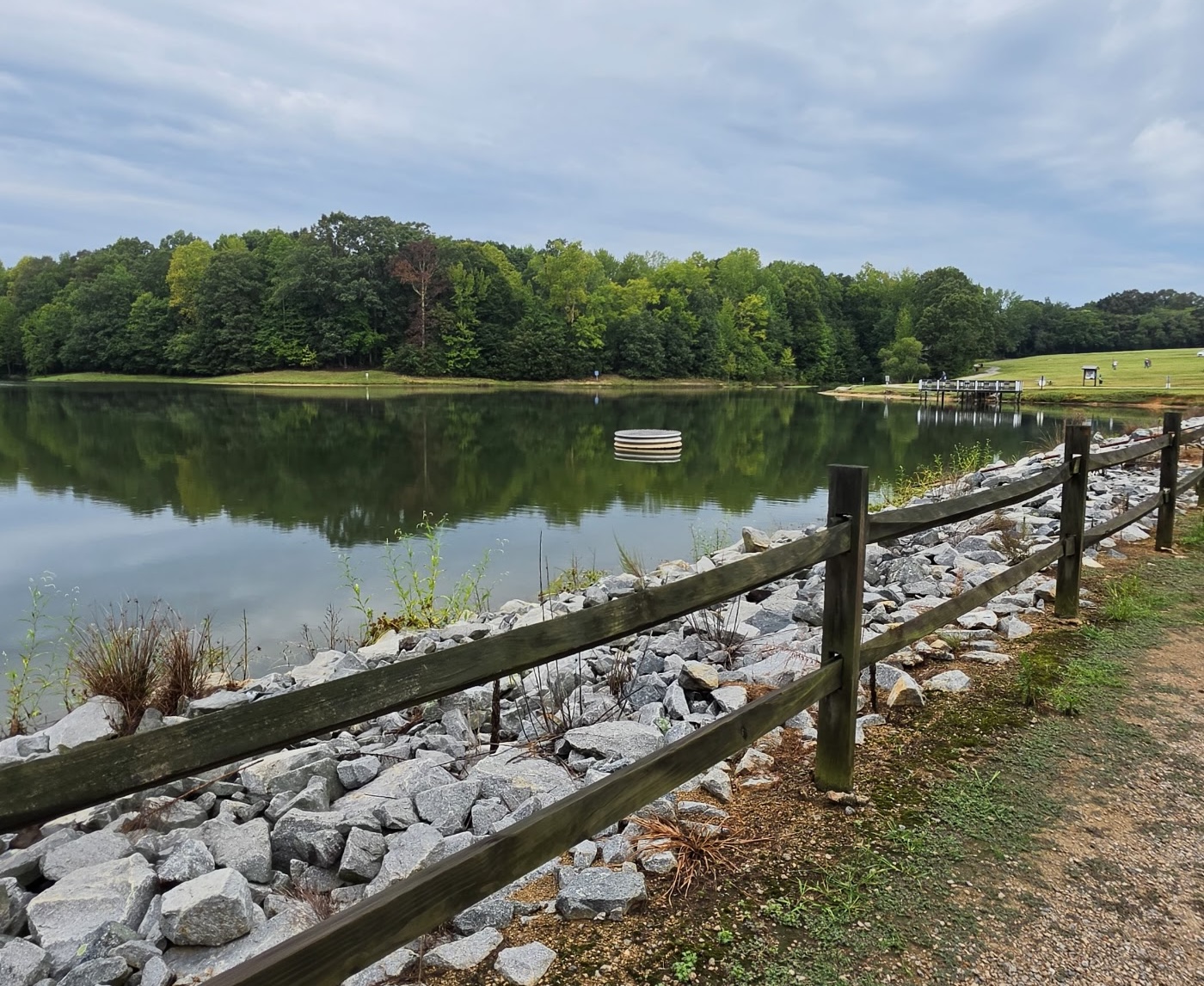 A lakeside trail with a wooden fence